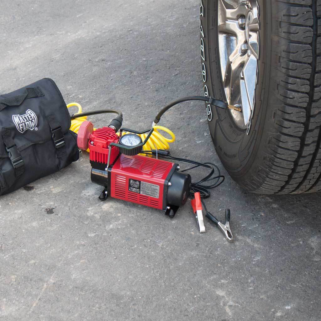 MasterFlow MF-1050 inflator on pavement in use inflating a truck tire.  With carry bag and battery clips
